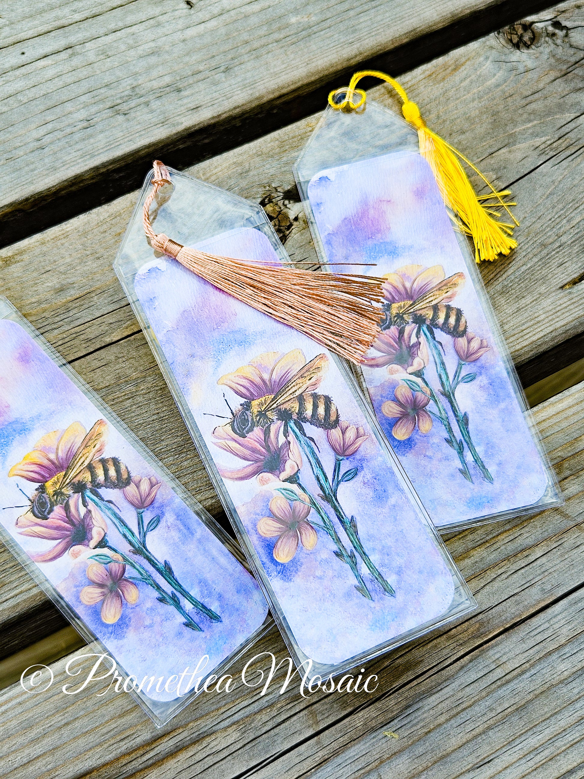 Bookmarks with bee and flower design on a wooden surface, featuring the brand 'Promethea Mosaic'.