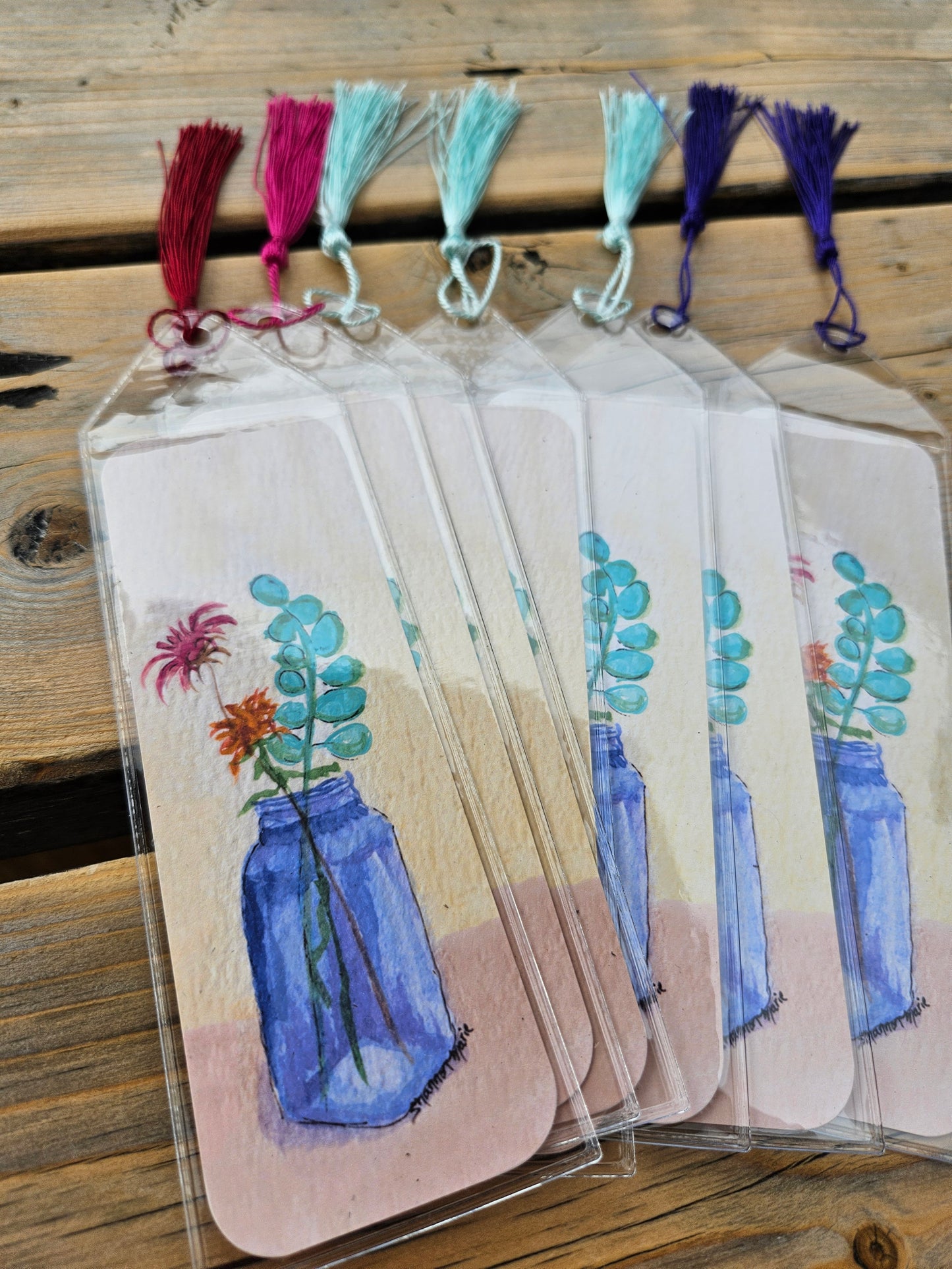 Several bookmarks with a print of a cobalt blue vase holding wildflowers with a light yellow background