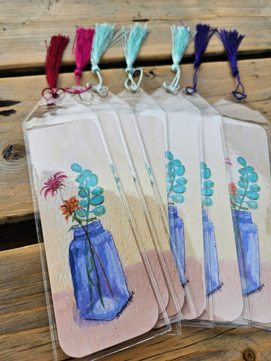 Several bookmarks with a print of a cobalt blue vase holding wildflowers with a light yellow background