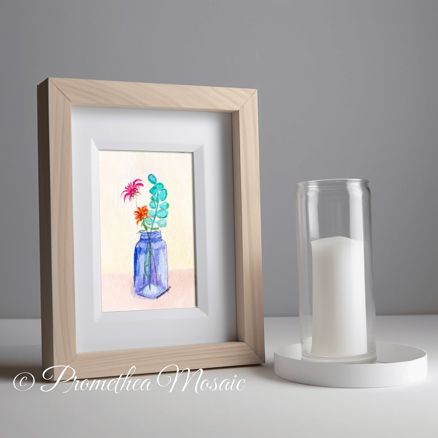 Framed artwork of flowers in a blue bottle next to a candle holder in kitchen on a gray background