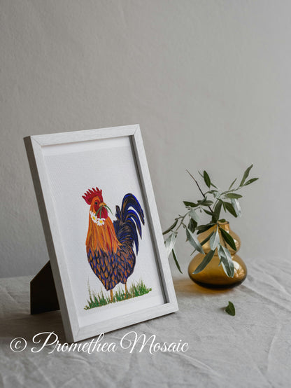 Framed artwork of a rooster on a gray surface with a vase and eucalyptus plant in the background.