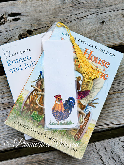 Love rooster bookmark in reusable clear plastic sleeve and tassel on stack of books