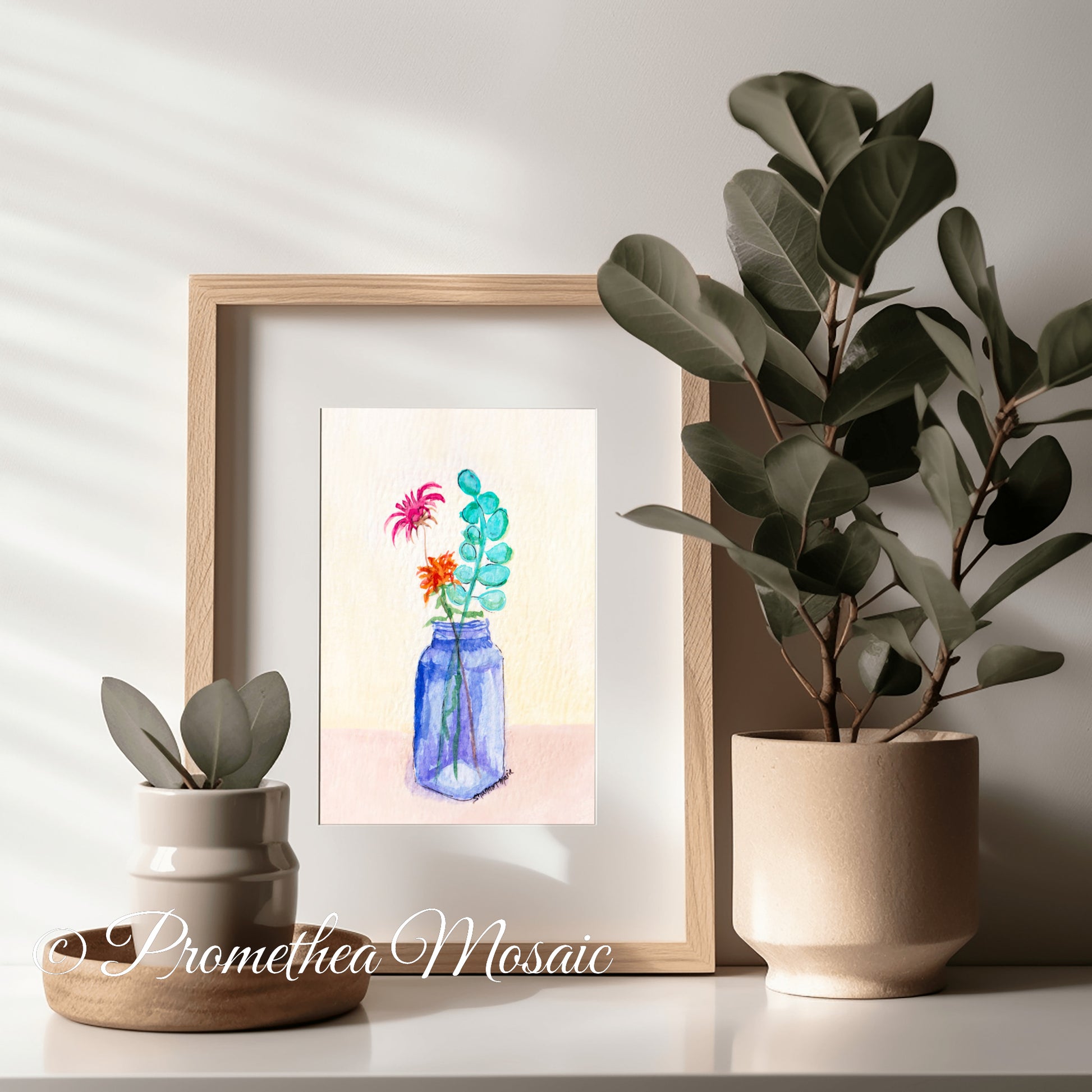 Framed eco-friendly art print of flowers in a blue vase on a shelf with plants on entryway table.