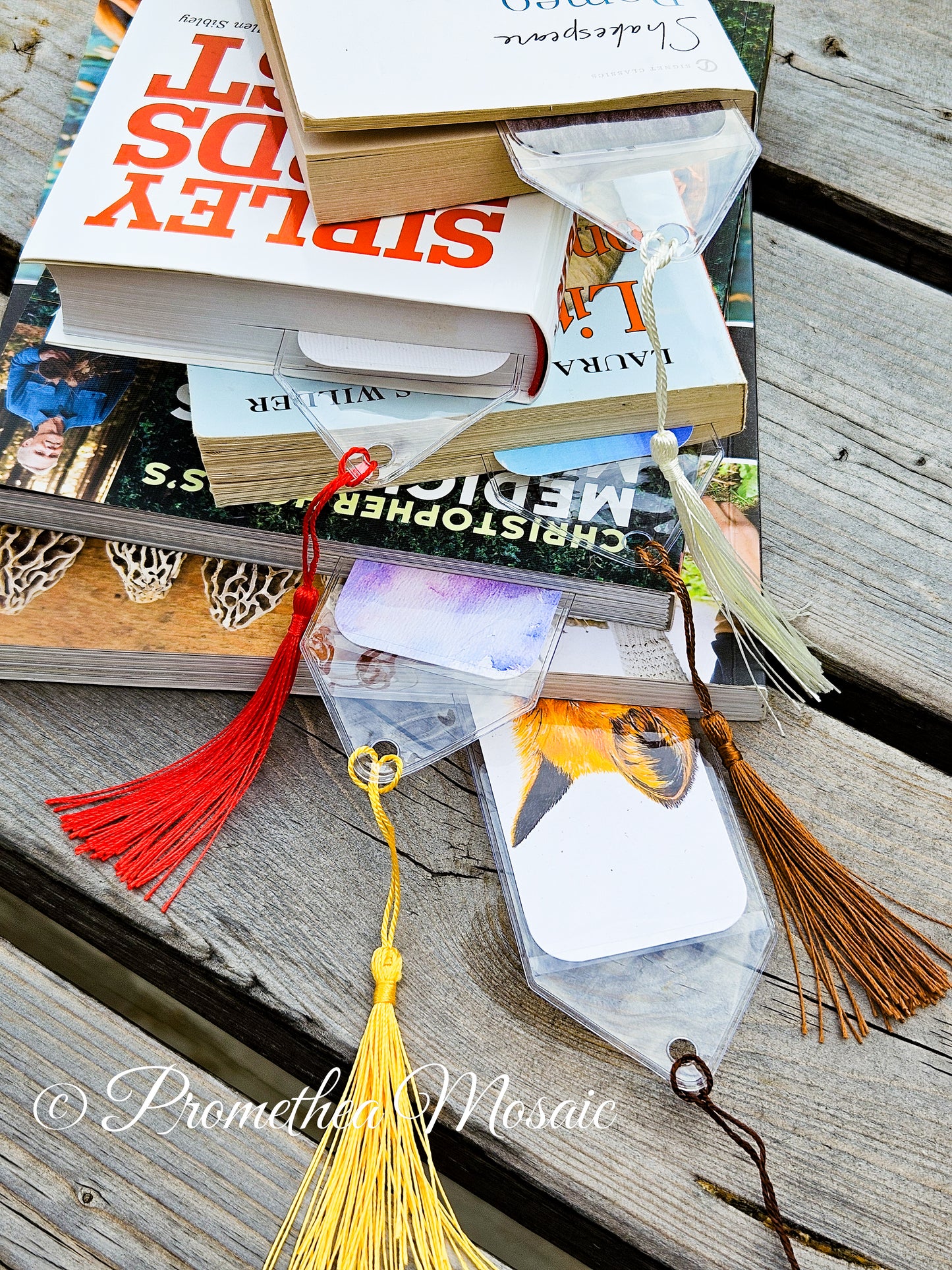 Stack of books with decorative bookmarks on a wooden surface
